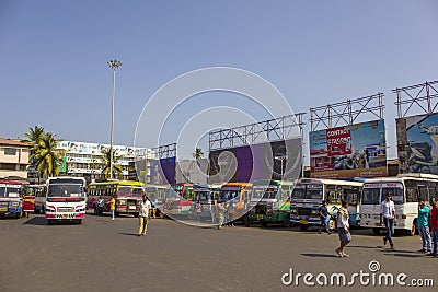Indian men wait near the parked bright colorful buses at the bus station Editorial Stock Photo