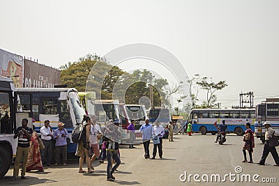 Indian people and european tourists walk in the bus station on the background of parked colorful Editorial Stock Photo