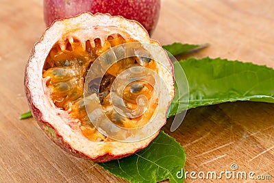 Maracuja cut in half and whole with leaf on wooden background. Passion fruit with fruit yellow juice and seeds Stock Photo