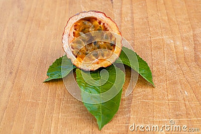 Maracuja cut in half and whole with leaf on wooden background. Passion fruit with fruit yellow juice and seeds Stock Photo