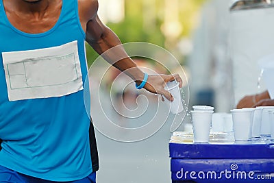 Marathon racer catching cup of water Stock Photo