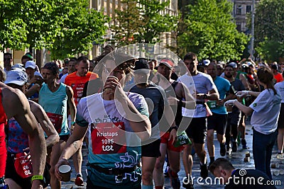 Riga, Latvia - May 19 2019: Marathon runner young man drinking water Editorial Stock Photo