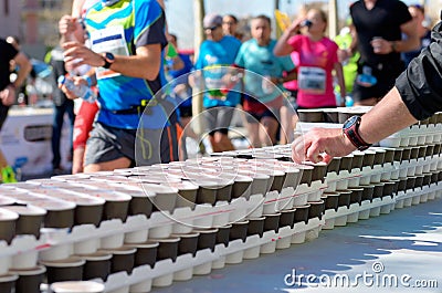 Marathon running race, runners on road, isotonic drinks on refreshment point Editorial Stock Photo