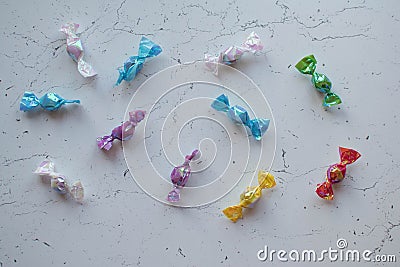 Marble background with multicolored caramels, candy in multicolored bright and different wraps, background celebration and candy Stock Photo