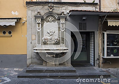 A marble fountain with entwined fish adorning a small store on a narrow street in Sorrento, Italy Editorial Stock Photo