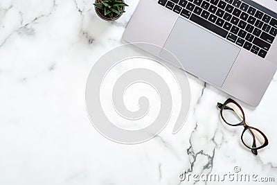 Marble office desk table with laptop computer, glasses, succulent plant. Minimal flat lay style composition, top view, overhead. Editorial Stock Photo