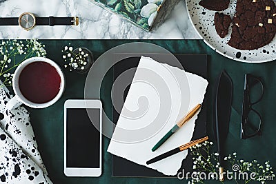 Marble pattern table with top view of empty paper with two quill pens, glasses, mug with tea and mockup phone Stock Photo