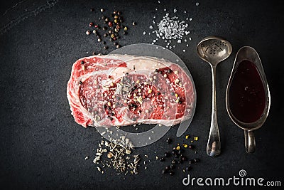 Marble ribeye steak, juniper, spoon, gravy boat on a blue-black Stock Photo