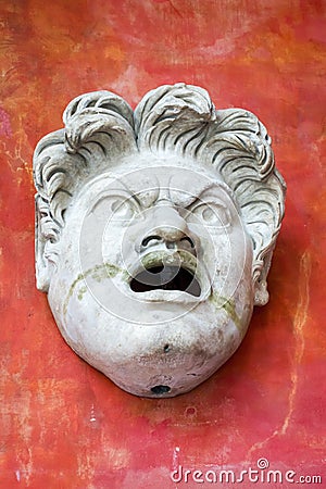 Marble sculpture of an angry face Roman or Greek against a red wall Editorial Stock Photo