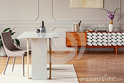 Marble table next to a chair in an eclectic dining room with a retro cabinet Stock Photo