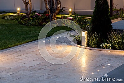 Marble tile playground in the backyard of flowerbeds and lawn with ground lantern. Stock Photo