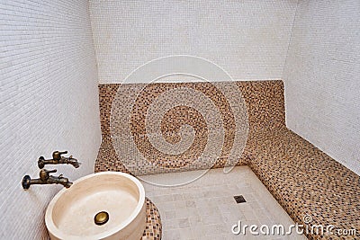 Marble washbasin with two taps opposite the mosaic sofa in the hammam Stock Photo
