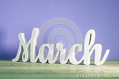 March - biginning of springtime concept. Wooden carved inscription on purple or dark pink background Stock Photo