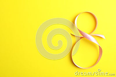 8 March, International Women`s Day. Figure eight of pink ribbon on yellow background Stock Photo