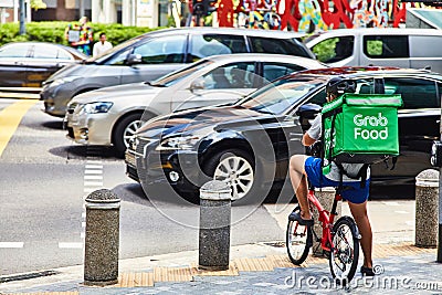 19 march, 2019 - Singapore: Courier for delivery of food `Grab` on a bicycle in Singapore Editorial Stock Photo