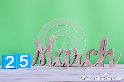 March 25th. Day 25 of month, daily wooden calendar on table and green background. Spring time, empty space for text. Stock Photo