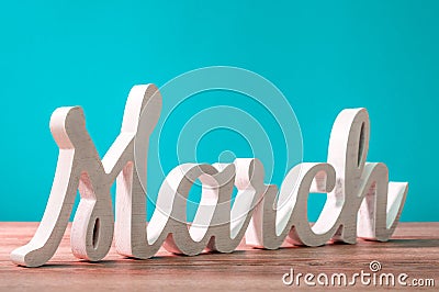 March - wooden carved word at turquoise background. Beginning of march month. Spring is coming Stock Photo