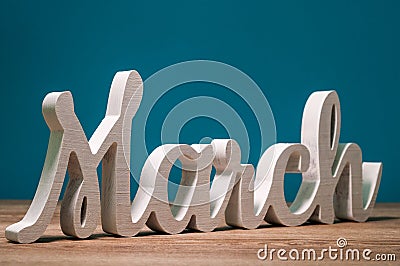 March -word carved of wood. march first spring month, calendar on blue background Stock Photo