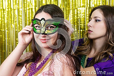 Mardi gras party. Woman with a green and yellow carnival mask and beads on the golden festive background Stock Photo