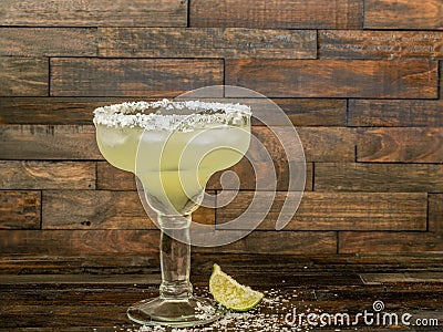 Margarita drink in a glass with a lime and a salted rim on a rustic wood background Stock Photo
