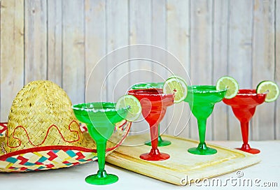 Margaritas in red and green glasses with salted rims and lime garnishes Stock Photo