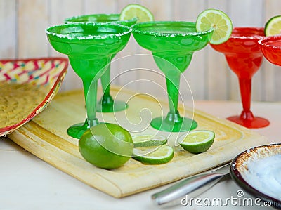 Margaritas in red and green glasses with salted rims and lime garnishes Stock Photo