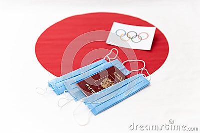 Mari El, Russia - June 16, 2021: Olympic flag on red round. The Russian passport and blue masks. The Japanese flag background. Editorial Stock Photo
