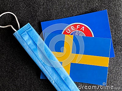 Mari El, Russia - June 12, 2021: UEFA logo and Sweden, Swedish flag is near a blue mask on the dark gray background. Tourist trip Editorial Stock Photo