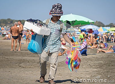 Hat vendor on the beach among crowds of unmasked people in Marina di San Nicola, Italy Editorial Stock Photo