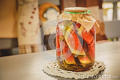 Marinated or pickled watermelon with herbs in a glass jar on a wooden table in a kitchen. Stock Photo