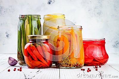 Marinated pickles variety preserving jars. Homemade green beans, squash, radish, carrots, red chili peppers pickles. Stock Photo