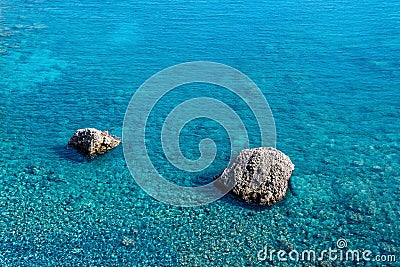 Marine background, transparent blue coastal littoral over coral reef and two rocks rise above the water Stock Photo