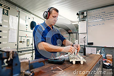 Marine electrical engineer officer in engine control room ECR. He works in workshop Stock Photo