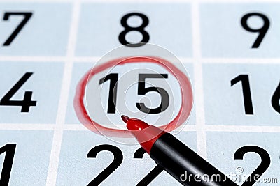 Marker pen over calendar with fifteenth day of the month highlighted by a red circle Stock Photo