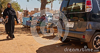 Market stall in Khartoum, with a small car and a woman in traditional black clothes Editorial Stock Photo