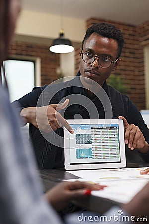 Marketing and research agency group leader pointing out business statistics data on tablet. Stock Photo