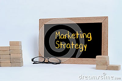 MARKETING STRATEGY inscription on blackboard. Eye glasses and Wood block stacking as step stair Stock Photo