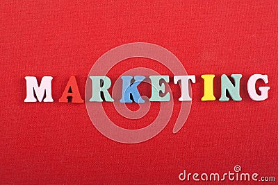 MARKETING word on red background composed from colorful abc alphabet block wooden letters, copy space for ad text. Learning Stock Photo