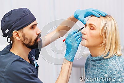 marking face of elderly woman old of plastic surgery at reception at doctor Stock Photo
