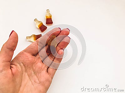 Marmalade candies. sweets in the shape of a bottle of lemonade lie on the hand of a girl with a red manicure. delicious, chewy Editorial Stock Photo