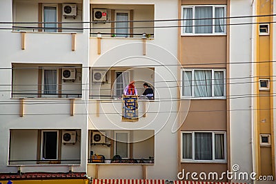 MARMARIS, TURKEY: A woman shakes a dirty carpet from the balcony of a multi-storey building. Editorial Stock Photo