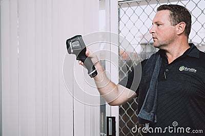 Maroochydore, Australia - March 5, 2020. Young Male Pest Control Worker checking apartment with FLIR E6 thermal imaging Editorial Stock Photo