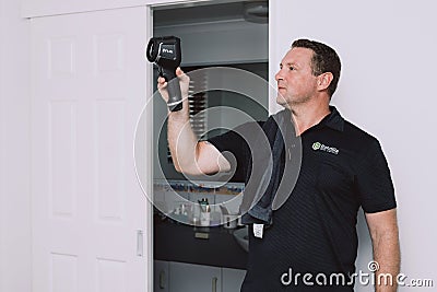 Maroochydore, Australia - March 5, 2020. Young Male Pest Control Worker checking apartment with FLIR E6 thermal imaging Editorial Stock Photo