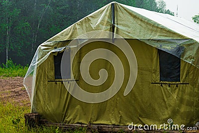 Marquee in the field. A tent for the accommodation of refugees. Green military tent Stock Photo