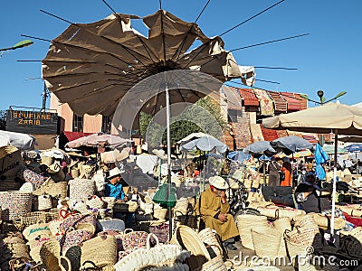 Marrakech, Morocco - December 31, 2019: Unknown local man selling straw baskets and bags at souk - typical Moroccan street market. Editorial Stock Photo