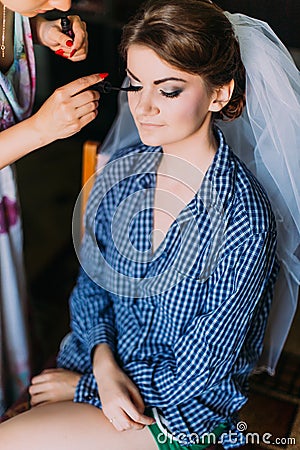 Marriage day moment. Applying make-up for beautiful young bride in dressing room Stock Photo