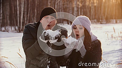 A married couple blowing out snow from their hands Stock Photo