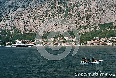 A married couple is kayaking, amicably rowing oars along Kotor Bay in Montenegro, against the background of the city of Editorial Stock Photo