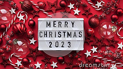 Marry Christmas banner concept. White board with text Marry Christmas 2023 among christmas red decor, balls, berries,striped candy Stock Photo