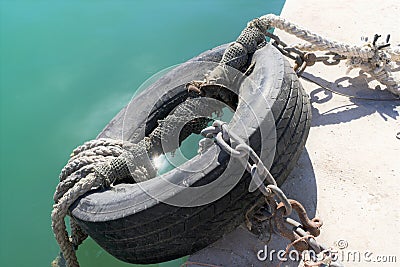 Marsaxlokk, Malta, August 2019. Old car tire, chains and ropes as a device for mooring ships. Stock Photo